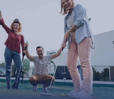 3 people playing mini-golf